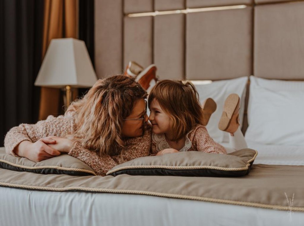 mama z córką leżą na hotelowym łóżku