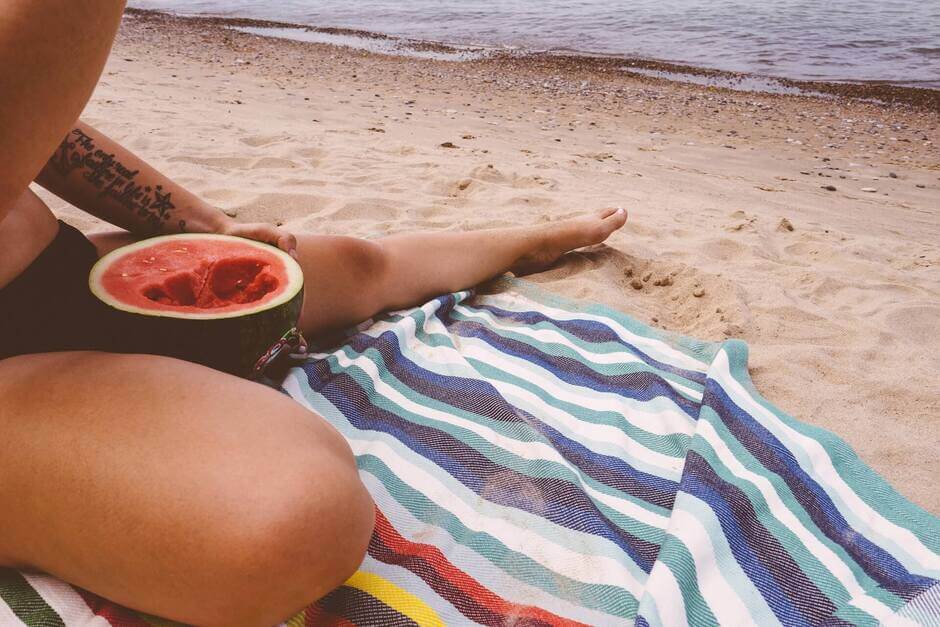 Kobieta jedząca arbuza na plaży