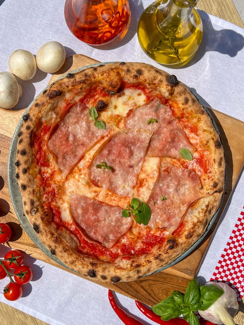 Pizza Cotto z szynką gotowaną i mozzarellą, podana na drewnianej desce