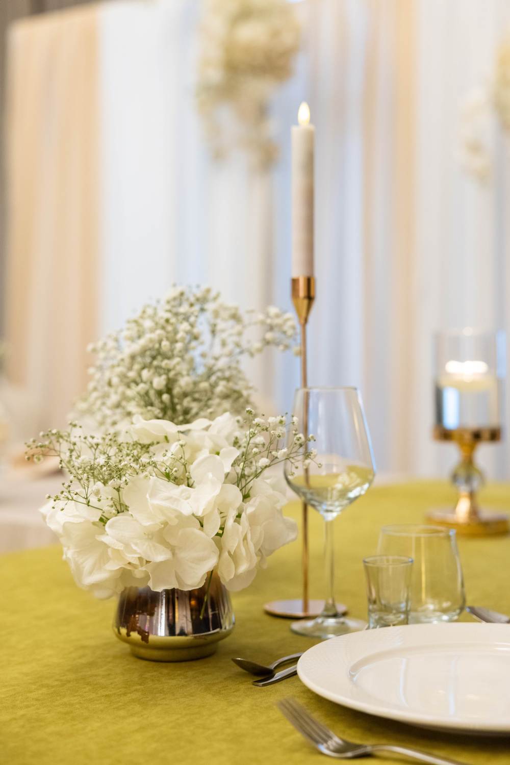 Eleganckie nakrycie stołu weselnego z białymi kwiatami i świecą